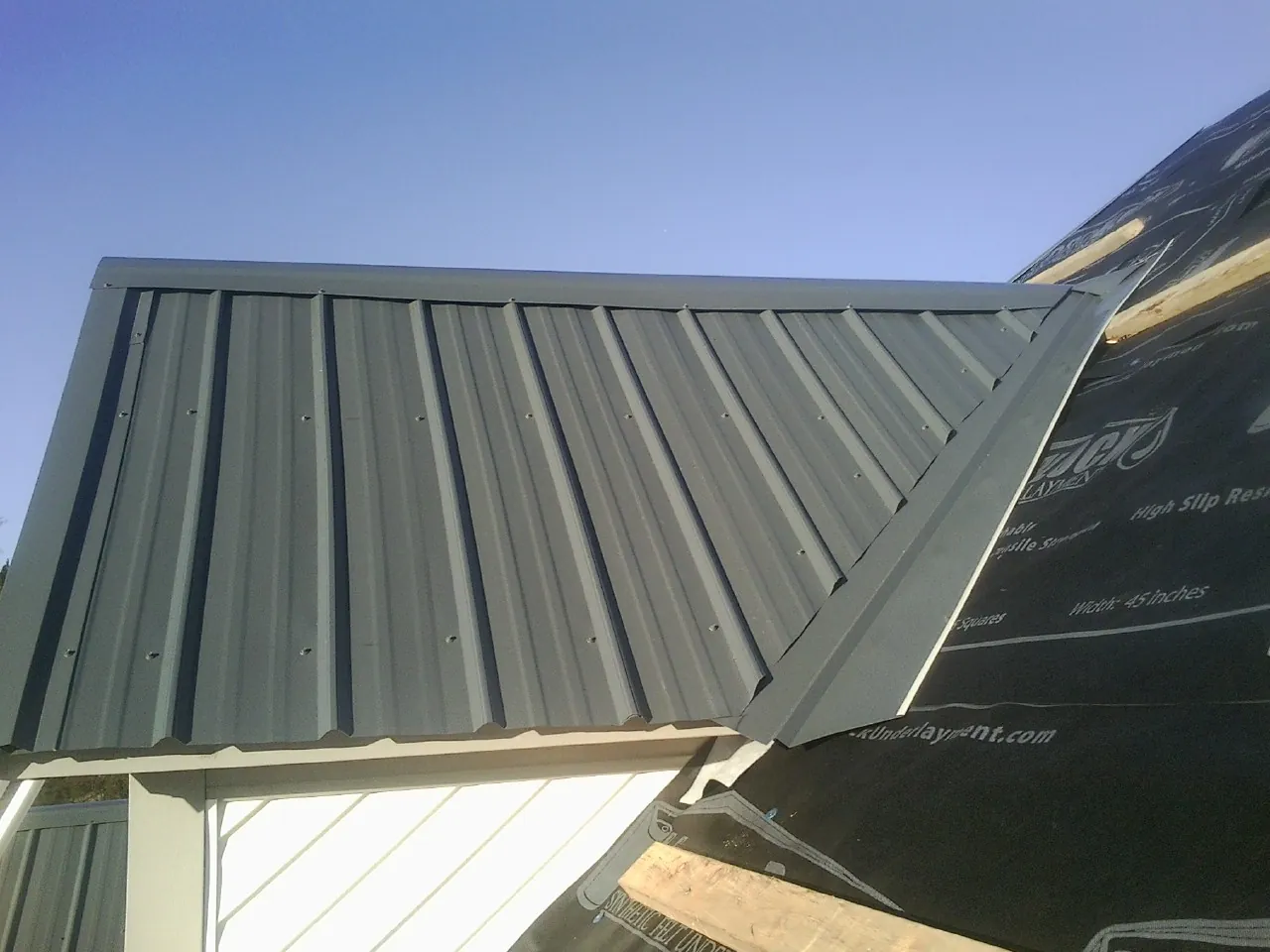 Gray metal roof panels going on over a garage gable in Pamplin