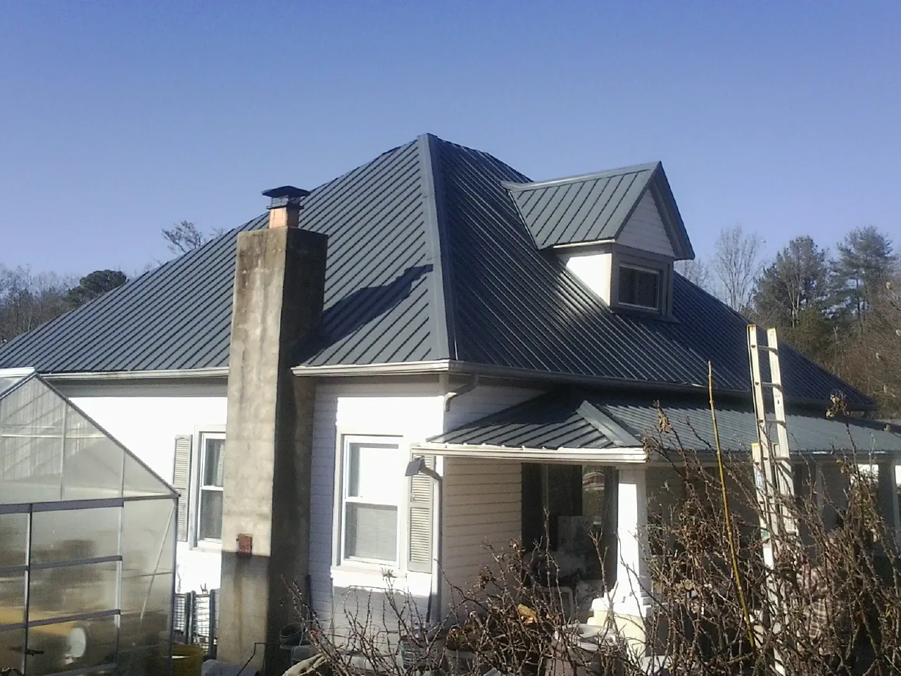 Dark blue standing seam metal roof on a white farmhouse with dormer — Slate & Tile Roof Repair by Roofing Brothers in Pamplin