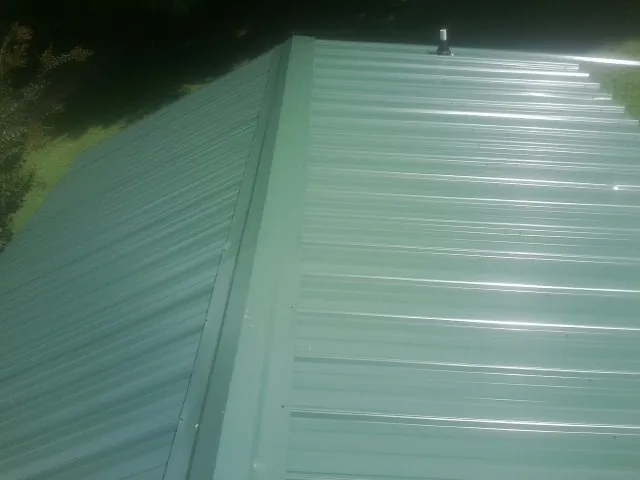 New green metal panels meeting at the ridge of a roof — Flat Roof Repair work by our crew in Pamplin