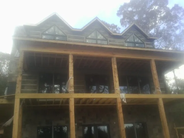 Dormers and porch framing on a large log home under construction — Roof Coating work by our crew in Pamplin