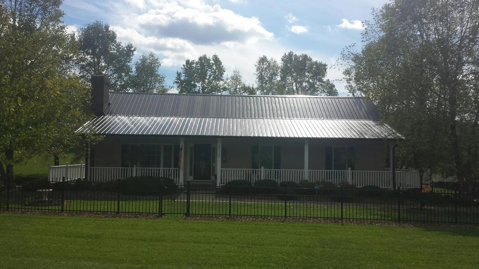 Gray metal roof on a brick ranch with a full width front porch — Gutter Guard Installation work by our crew in Pamplin