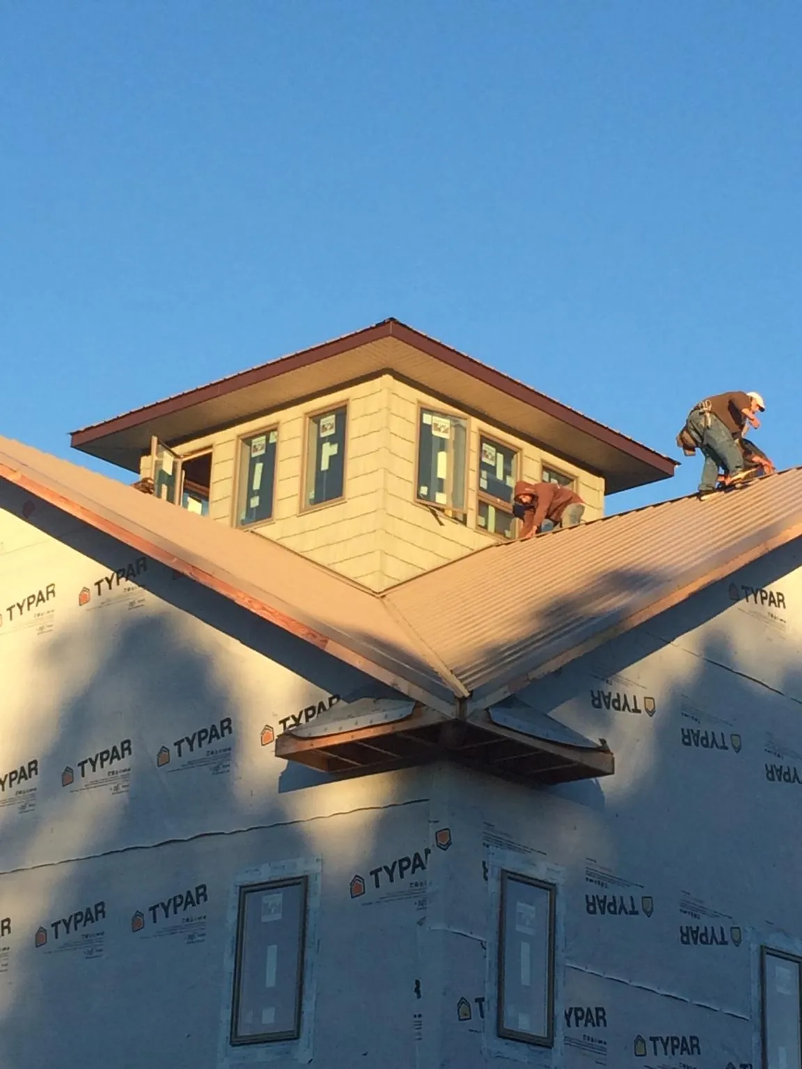 Roofers working around a rooftop cupola on a new metal roof at sunset — Roof Waterproofing in Pamplin by Roofing Brothers